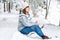 Woman with a cup of tea in her hands siting in in snow-covered forest