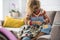 Woman with curly hair sitting on sofa using a seam ripper to rip out thread of the seam of a woollen fabric. Young woman using