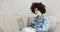 Woman with curly hair writing message in social media on laptop sitting on sofa.