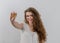 A woman with curly long hair holds a physical bitcoin cryptocurrency in her hand. White background