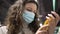 Woman customer in a medical mask reads the composition on a bottle of oil in a supermarket close-up