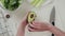 Woman cuts avocado on a white cutting board