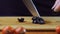 A woman cuts black olives with a kitchen knife. Slow motion.