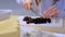 Woman cuts black olives on plastic board, hands close-up.