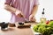 Woman cuts black olives. The process of making salad