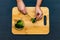 A woman cuts broccoli with a knife on a cutting Board. Healthy food