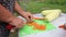 A woman cuts carrots on a cutting board. Cooking outdoors