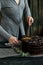 Woman cuts chocolate cake close. Dark tones