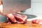 A woman cuts fish fillet with a large knife at home in the kitchen