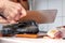 A woman cuts fish with a large knife at home in the kitchen