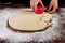 Woman cuts out dough circles with round mold for making buns, dounuts
