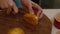 Woman cuts persimmon on a round wooden board. View from above.