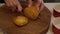 Woman cuts persimmon on a round wooden board. View from above.