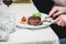 Woman cuts a piece of fresh grilled bbq roast beef steak. soup sauce small jug glass served on a table in a restaurant