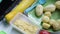 The woman cuts the potatoes and puts them on top of the pieces of chicken fillet that lies on the baking sheet.