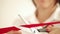 Woman cuts a red tape with scissors ceremonially