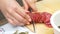 Woman cuts sausage on wooden chopping Board