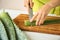 Woman cutting aloe vera leaf on wooden board, closeup