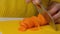 Woman cutting carrot on table, close-up. Hands cutting carrots on a cutting board. Young woman cutting vegetables in the