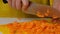 Woman cutting carrot on table, close-up. Hands cutting carrots on a cutting board. Young woman cutting vegetables in the