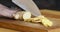 Woman cutting fresh ginger root on kitchen table, close up