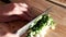 Woman is cutting green onion with knife on wooden board. Food ingredients salad