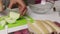 The woman is cutting the onion. The chopped fat lies on the board. Container contains parsley and garlic. Salted lard with herbs