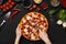 Woman cutting pepperoni pizza into slices, top view