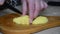 A woman is cutting potatoes on a cutting board