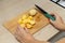 woman cutting potatoes on a kitchen board.