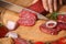 Woman cutting smoked sausage on wooden board, closeup