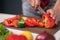 Woman cutting sweet pepper or bell pepper using knife on plastic cut board. Freshly cut vegetables for fresh salad