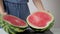 Woman cutting watermelon in half with big knife showing watermelon flesh