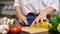 Woman is cutting yellow pepper on cut board on kitchen in slow motion