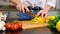 Woman is cutting yellow pepper on cut board on kitchen in slow motion