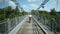 Woman cycling on road over suspension bridge