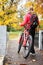 Woman cyclist with bike and backpack in autumn park