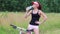 Woman cyclist in cap drinks pure water at summer in forest