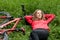 Woman cyclist relaxes lying among the green grass