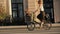 Woman cyclist walking beside riding bike on city road. Woman bike city