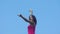 Woman dancer in red dress makes slow movement on blue sky background pretty lady