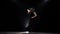 Woman dancing a incendiary dance. Black background. Llight from behind