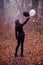 Woman in dark clothing in autumn foggy forest, with two balloons, black and white. Concept of choice, good and evil