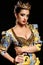 Woman with dark hair in luxurious gold dress with bijou and crown,