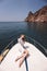 woman with dark hair in luxurious white dress relaxing on the deck of yacht, sailing in mediterranean sea