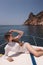 woman with dark hair in luxurious white dress relaxing on the deck of yacht, sailing in mediterranean sea