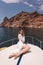 woman with dark hair in luxurious white dress relaxing on the deck of yacht, sailing in mediterranean sea