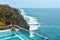 Woman with dark hair relaxing in transparent swimming pool with fantastic ocean view