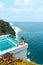 Woman with dark hair relaxing in transparent swimming pool with fantastic ocean view