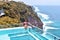 Woman with dark hair relaxing in transparent swimming pool with fantastic ocean view